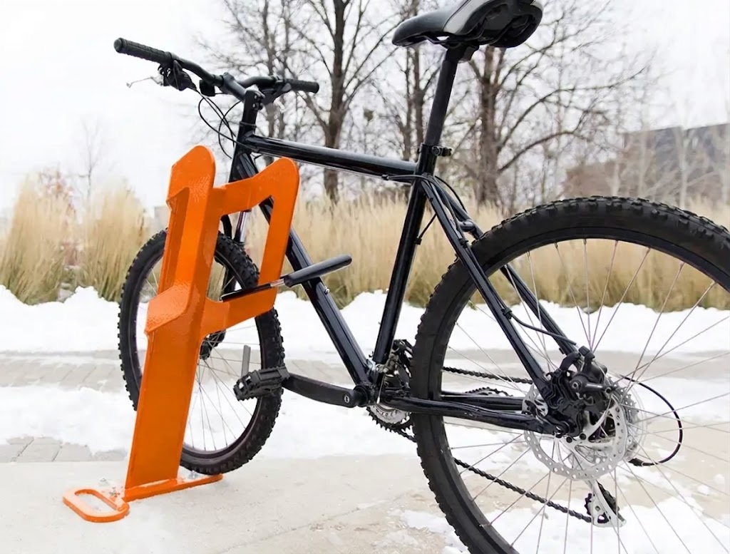 Orange open bike rack securing a mountain bike in an outdoor setting